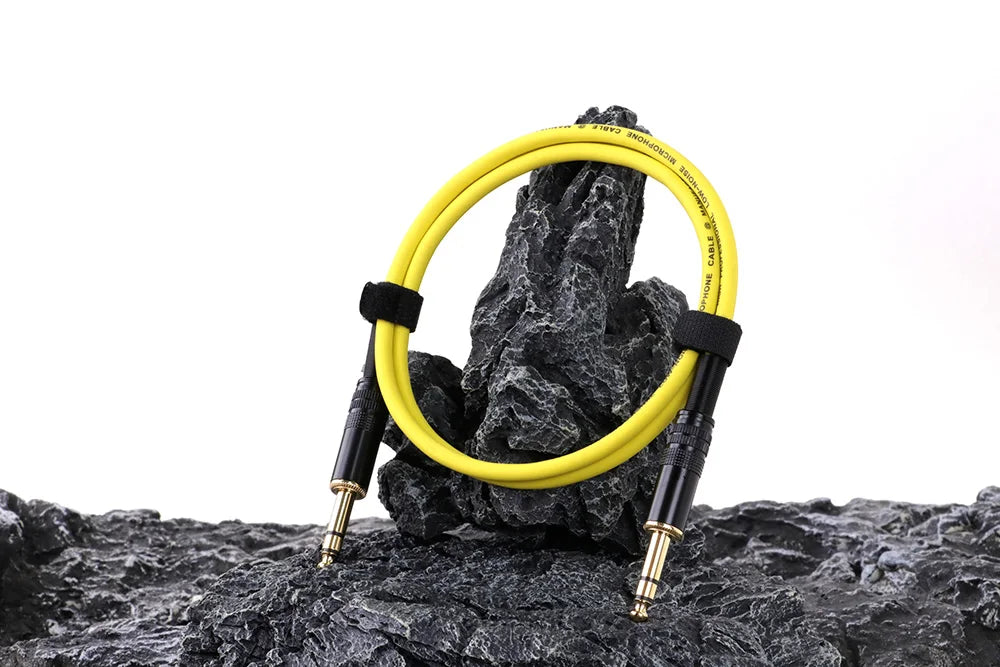 Yellow guitar cable coiled on a rock with a white background
