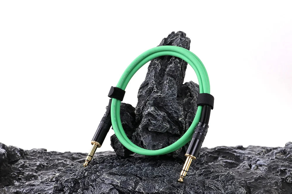 Green audio cable coiled on a rock with a white background