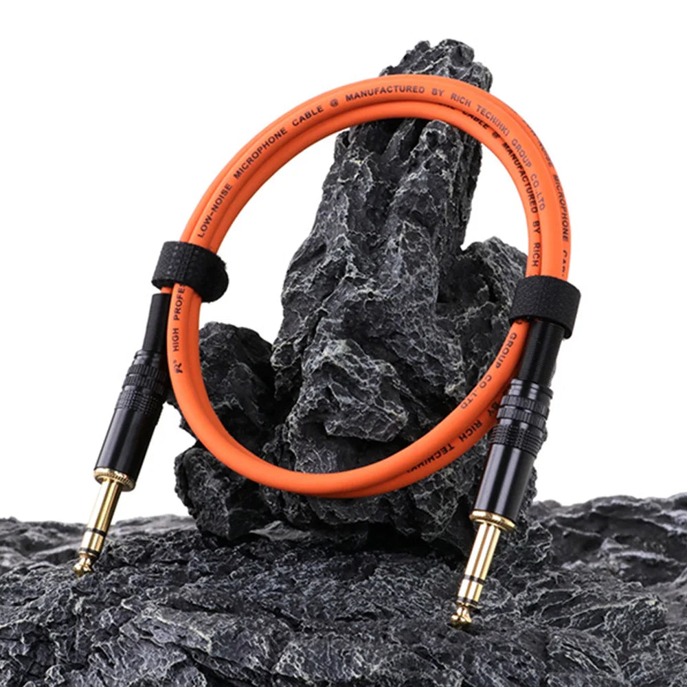 Orange audio cable with black connectors on a rocky surface