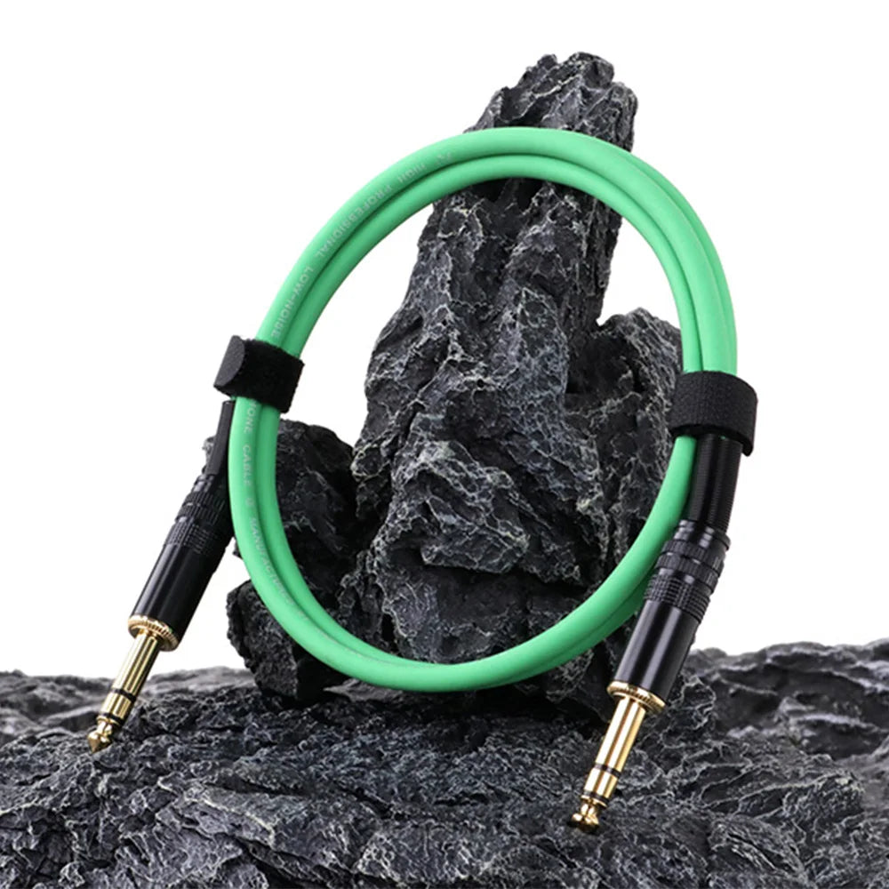 Green audio cable with black connectors on a rocky surface