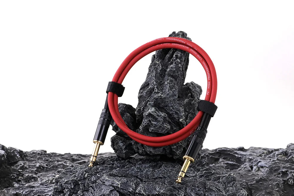 Red audio cable coiled on a rocky surface with a white background