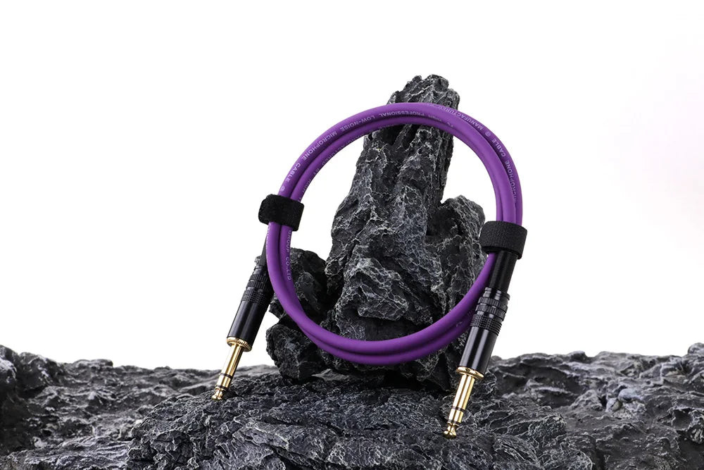 Purple guitar cable coiled on a rock with a white background